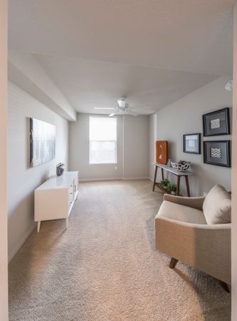 Model living room at our apartments in Delray Beach, featuring carpeted floors, a white chair, and modern decor.