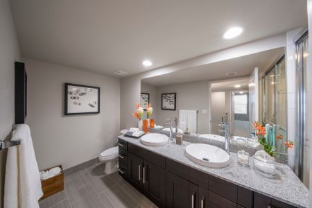 Model bathroom at our apartments in Delray Beach, featuring floor tiles, granite countertops, and a large mirror.