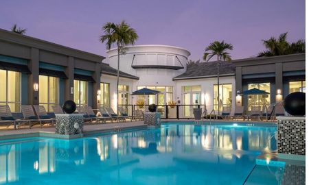 The pool area at our apartments in Delray Beach at night, featuring beach chairs, umbrellas, and pool lights.