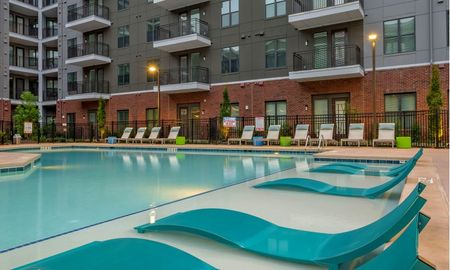 Pool area at our apartments in Sandy Springs, featuring pool chairs, a shaded area, and reclining beach chairs.