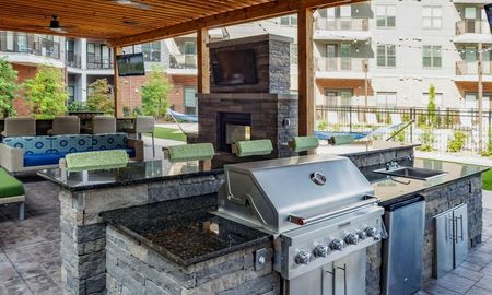 Outdoor lounge at our apartments in Sandy Springs, GA, featuring cushioned chairs, grills, and a fireplace.