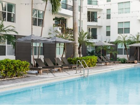 Outdoor pool with lounge chairs at an East Pompano apartment.