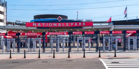 The entrance to the Nationals Park area, featuring a large sign, entrance gate, and view of the street.