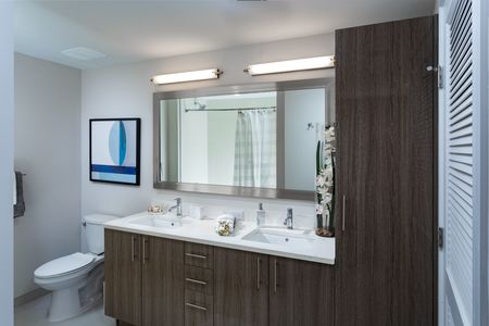 Model bathroom at our apartments in Fort Lauderdale, featuring wood laminate cupboards and white countertops.