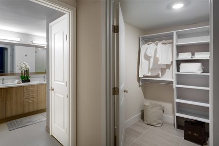 Model bathroom and closet at our apartments in Fort Lauderdale, featuring a walk in closet with hanging robes.