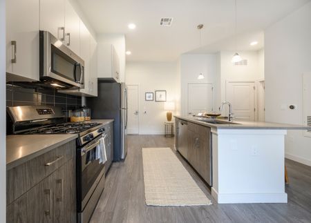 Model kitchen at our apartments in Waterdown, featuring wood grain floor paneling and stainless steel appliances.