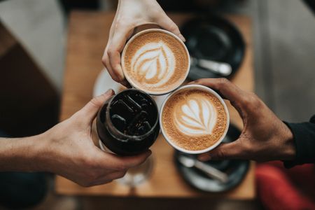 hands holding coffee cups cheersing