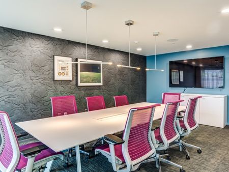 Conference room and co working space at our apartments in Cambridge, featuring a conference table with pink chairs.