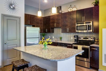 Interior of a luxury apartment near Stoneham MA with a beautiful kitchen equipped with an island, granite countertops, and dark wood cabinetry.