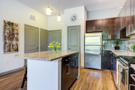 Model kitchen at our apartments in Wakefield, featuring wood grain floor paneling and stainless steel appliances.