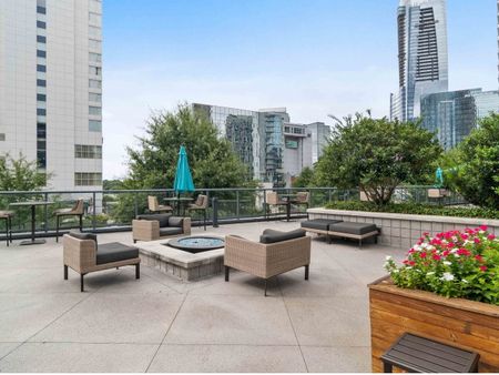 Rooftop lounge at our apartments in Atlanta, featuring cushioned outdoor chairs, a fire pit, and a view of the city.Outdoor lounge at our apartments for rent in Atlanta, featuring outdoor couches, a fire pit, and a view of the city.