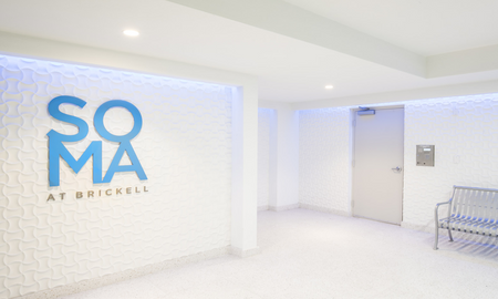 Entrance to SOMA at Brickell Apartments for rent in Miami, featuring white hallways and a modern decor.
