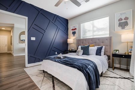 Model bedroom at our apartments for rent in Mooresville, NC, featuring a blue wall and window with blinds.