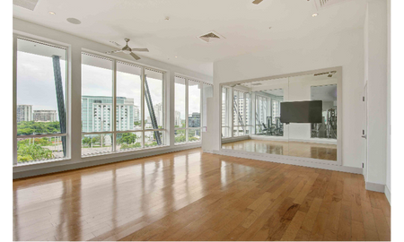 Fitness center at our apartments for rent in Brickell, featuring wood grain flooring and mirrored walls.