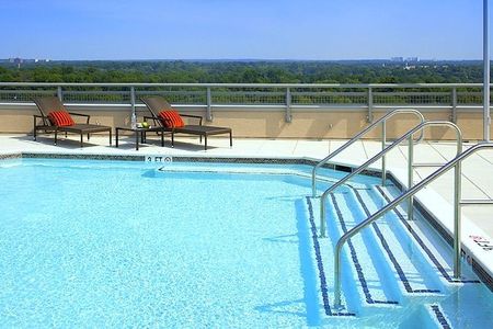 The pool deck at our apartments for rent in Silver Spring, featuring two beach chairs with pillows and a view of the forest.