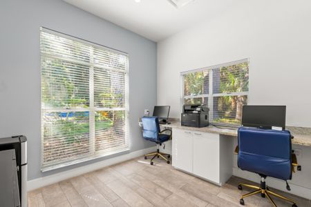 Business center with two desktops and large windows.
