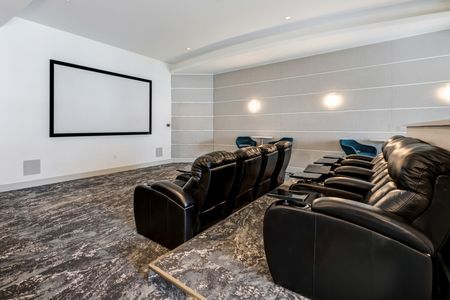Screening room and theater at our apartments in Miami, featuring chairs, counter seating, and a large screen