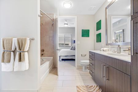 Model bathroom at our apartments for rent in Boca Raton, featuring tiled flooring and a view of the bedroom.