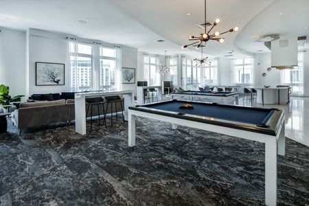 Entertainment area and lounge at our apartments in Brickell, featuring a billiards table, marble tiled floors, and couches.