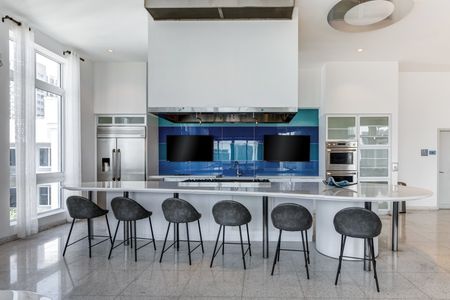Resident lounge at our apartments for rent in Brickell, featuring a counter seating, two TV, and two ovens.