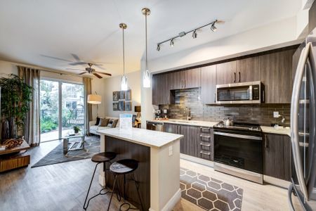 Model kitchen at our apartments for rent in Brickell, featuring wood grain floor paneling and stainless steel appliances.