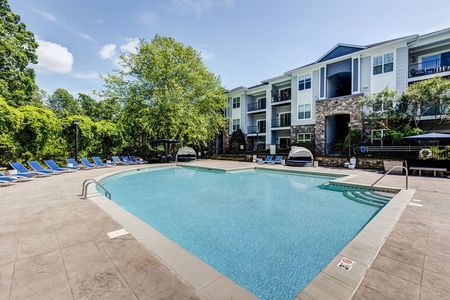 The pool area at our apartments for rent in Mooresville, NC, featuring beach chairs and a view of the apartments.