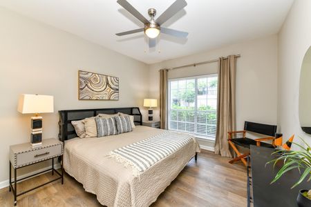 Bedroom with large window, ceiling fan, and wood plank flooring