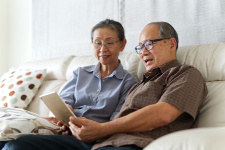 woman and man sitting on a couch and looking at a tablet