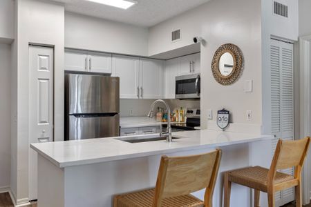 Luxury Palm Beach Gardens apartment kitchen with white wood cabinetry and wood flooring.