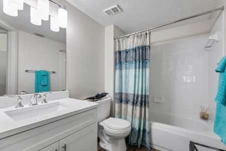 Model bathroom at our apartments in Palm Beach Gardens, featuring white countertops and a bath / shower combo.