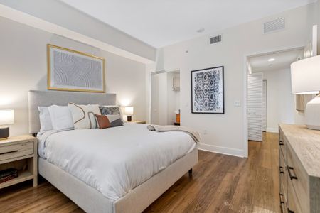 Model bedroom at our apartments in Boca Raton, featuring carpeted flooring, a large window, and elegant decor.