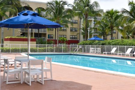 Country Club Towers, exterior, sparkling blue pool, blue lounge chairs, picnic table with umbrella, palm trees