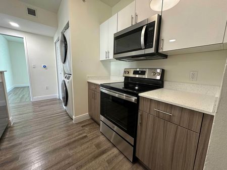 Kitchen with Two-Toned Cabinetry, Stainless Steel Appliances, and Washer/Dryer Unit