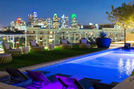 pool with furnishing on rooftop at nighttime with downtown views