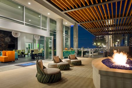 lit firepit and furnished clubroom and rooftop area at nighttime