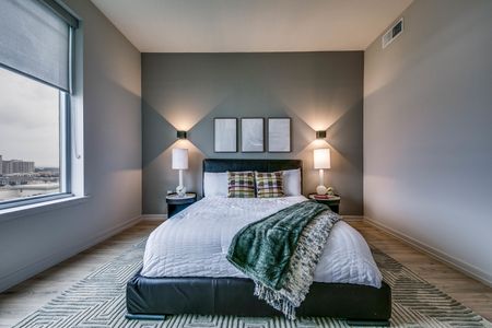 Furnished bedroom with wood flooring and natural and upgraded lighting