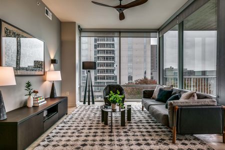 Furnished living room with floor to ceiling windows and views of downtown and roller shades