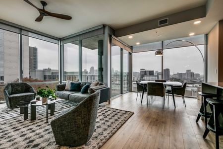 Furnished living room with wood flooring and floor to ceiling windows with roller shades and views of downtown