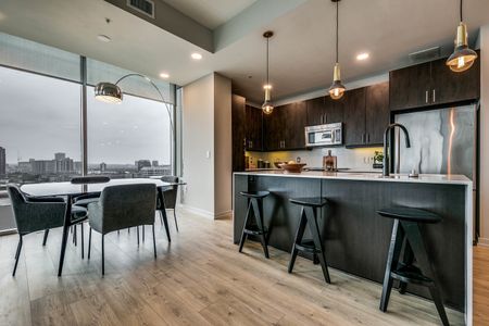 Dining area with background downtown views next to kitchen with waterfall island and rich lighting