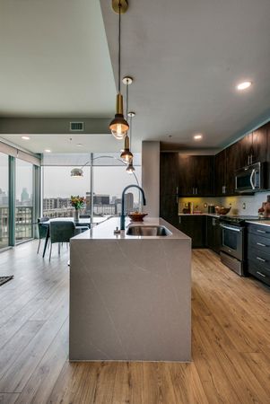 Waterfall kitchen island with matte black goose neck faucet and Soapstone Mist Quartz Countertops overlooking dining area and kitchen with downtown views in background