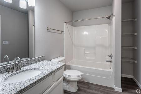 newly renovated bathroom with shower, wood flooring, shelving, granite countertops
