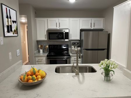 Pet-Friendly Apartments in Hermitage, TN - Highlands at the Lake - Kitchen with Stainless Steel Appliances, White Cabinets, White Tile Backsplash, Marble Countertops, and Stylish Decor