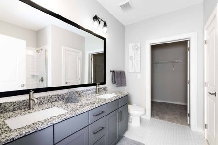 Apartments in Nashville TN - The Sound at Pennington Bend - A Bathroom With Two Sinks And A Large Mirror With Grey Cabinetry, White Walls, And White Tile Flooring