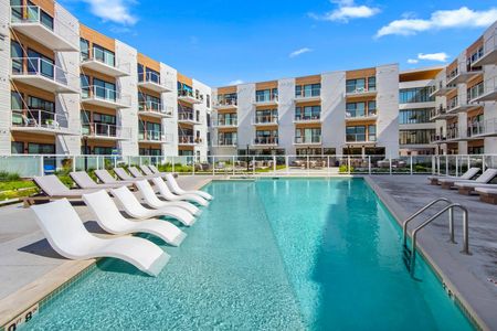 Pet-Friendly Apartments In Oak Creek, WI - Parterre At Emerald Row - Pool With White Lounge Chairs, Fenced Area, And View Of Apartment Complex