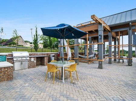 Apartments Near Donelson Nashville TN - The Sound at Pennington Bend - An Outdoor Community Area With Covered Tables And Chairs, A BBQ With Counter Space, And A Couple Hammocks All Surrounded By Greenery