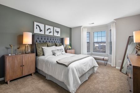 Furnished model bedroom with a queen sized bed and oversized bay windows