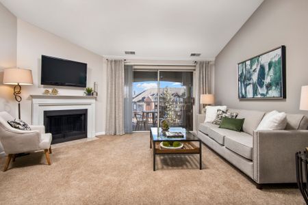 Furnished model living room with a balcony view, fireplace and flat-screen TV