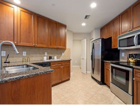 Kitchen with back splash, cabinets, sink, stainless steel refrigerator, microwave, oven, and dishwasher