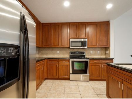 Kitchen with back splash, stainless steel refrigerator, microwave, and oven