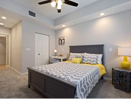 Furnished bedroom with bed, nightstand, desk, and ceiling fan